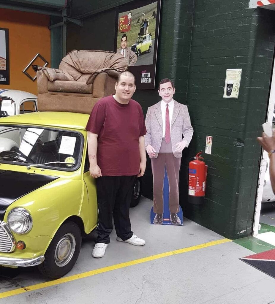 Steven standing between a yellow mini and a full sizes cardboard cut out of Mr Bean